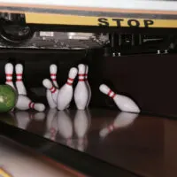 The bowler rolls the green bowling ball down the lane, missing the pocket with a weak hit and hitting the rear pin, leaving a cluster of three pins 2-4-5 .
