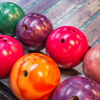 An orange colorful reactive resin bowling ball with various colors of plastic balls.