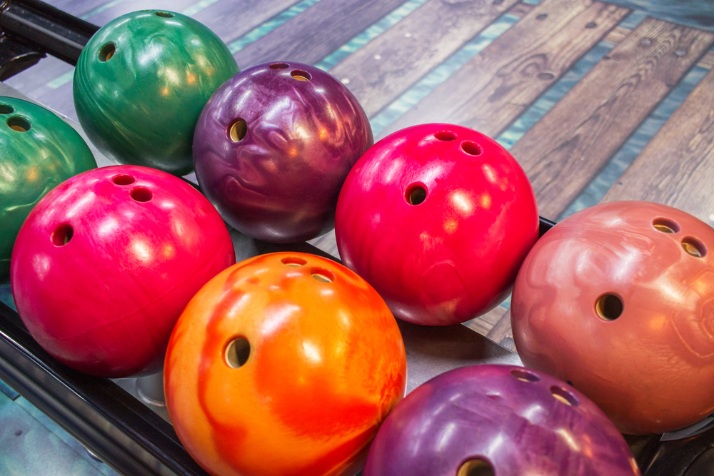 An orange colorful reactive resin bowling ball with various colors of plastic balls.