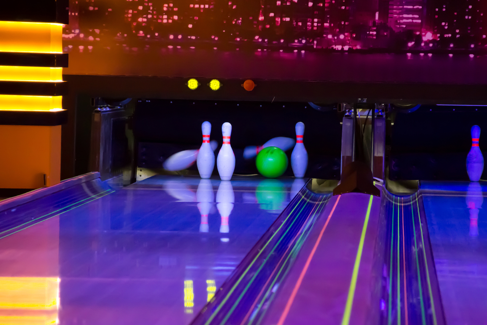 A bowling lane where the neon green ball hit all the pins and left the 2,4, and 10 pin on the back row (the corner pin).