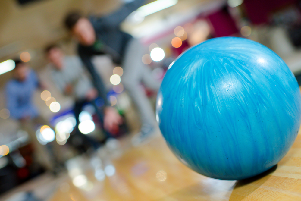A professional bowler, who is cheered on by teammates, uses their own ball instead of a house ball to secure the win.