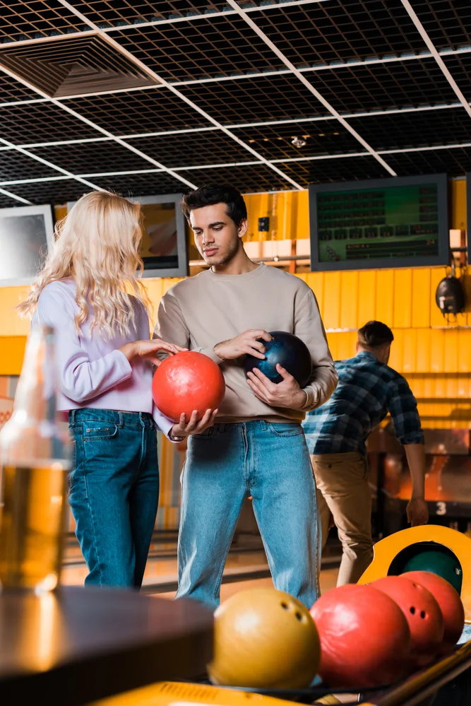 The guy holding the blue ball decided to take bowling leagues to help improve his bowling score.