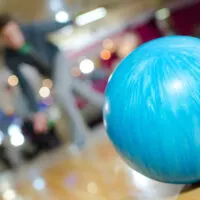 The bowler lined his dominant foot and rolled the blue ball in the bowling competition, hitting all ten pins.