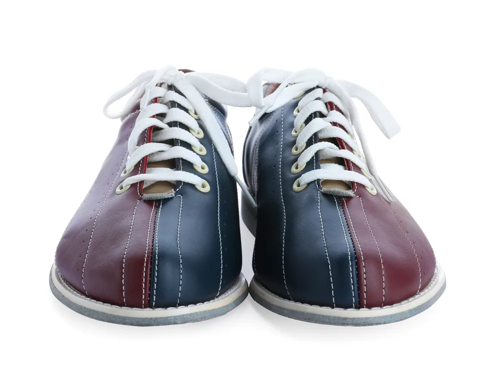 The pair of bowling shoes, isolated on white background, was repaired when the left shoe's heel was damaged.