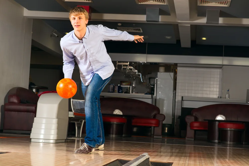 The bowler in the light blue shirt, with the orange ball decided to improve their bowling game by taking private lessons.