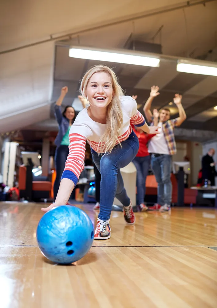 A lady in a white and red striped sweater is bowling in her first trimester.