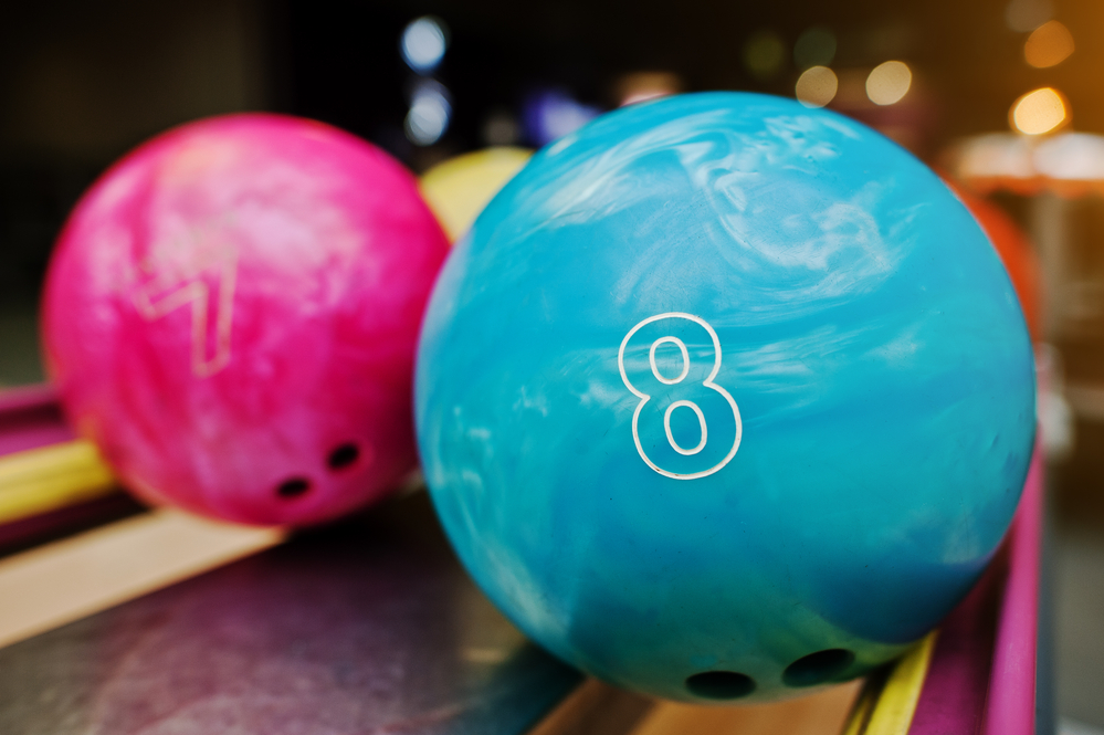 The 7 and 8-pound bowling balls sitting on the ball return can knock down bowling pins.