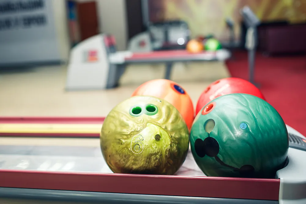 Bowling balls that are custom drilled bowling balls sit on the ball return.
