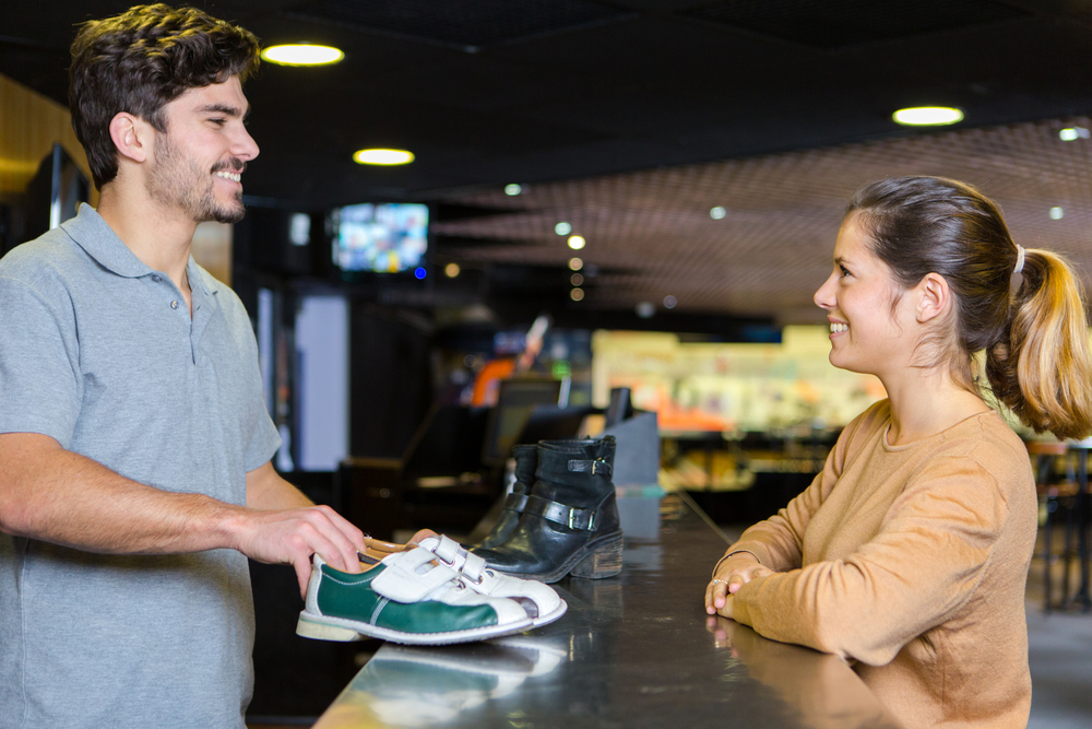 The round1 staffer offers the lady great customer service regarding prices.