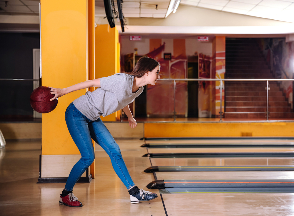 The alley offer bowling lessons and the lady with the red ball plans to take lessons.