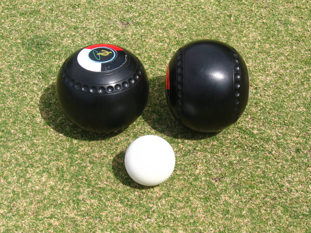 Black lawn bowls and a white jack are used doing traditional lawn bowling matches.