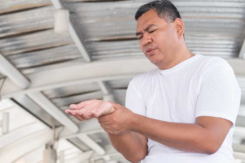Can You Bowl With Arthritis In Your Hands, Wrists, Or Knees? 1 Senior man suffering wrist issues and discomfort with his ring finger and thumb, causing trouble gripping the ball.
