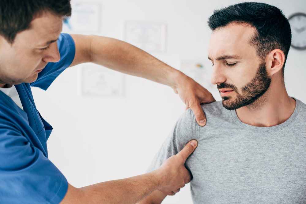 A male is getting massage therapy after experiencing shoulder tendonitis after undergoing rotator cuff surgery.