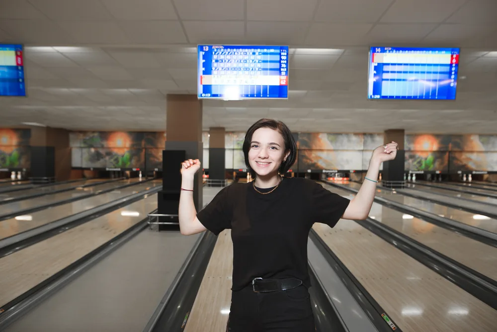 A happy young female after leaving a single pin on the last shot leading to a 299 score requiring a little luck.