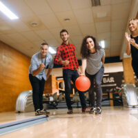 Home bowling alley with ball ramp, modern interior design, and classic bowling alley couches in the background.