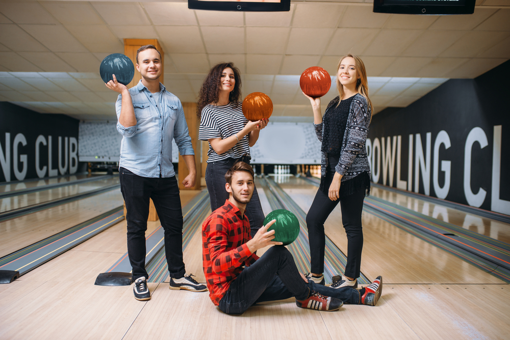 Bowling team posing for a photo on wooden bowling lanes in front of a ball ramp.
