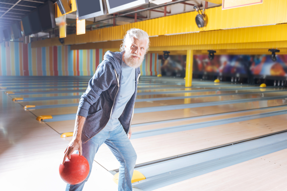 An old man at the bowling alley that's participating in a prospective study with an id card.