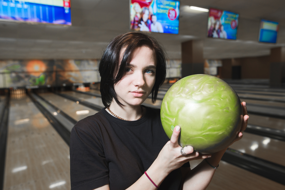 A young lady is preparing to throw the final ball during the tenth frame as she targets an extremely difficult certain score.