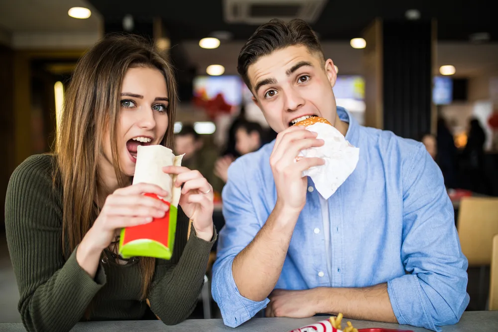 A woman and man enjoying food and beer at the bowling alley.