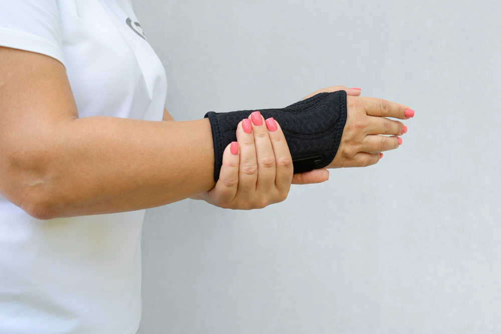 A female bowler is wearing wrist support equipment to practice bowling for the first time since having wrist surgery.