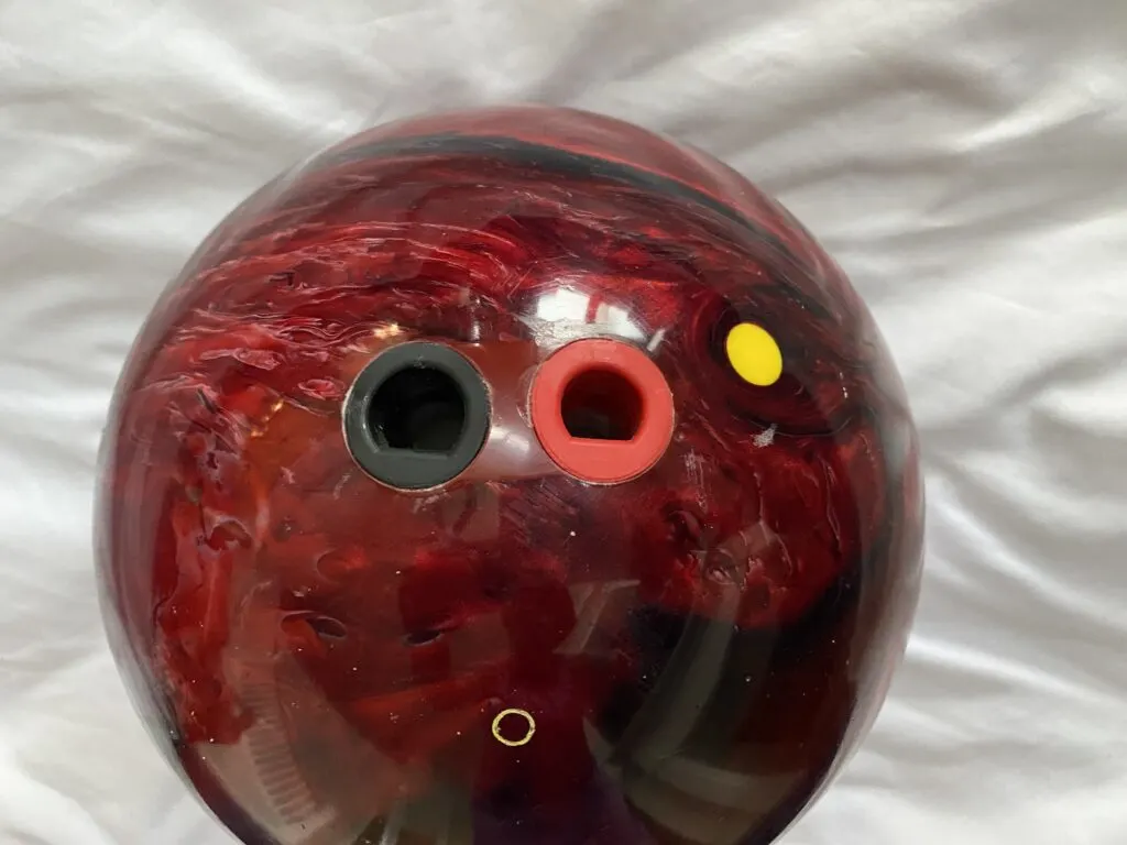 Do Pro Bowlers Use Finger Inserts? What Are Inserts For? 1 A black and red bowling ball with fingertip grip holes drilled that has thumb inserts giving pro bowlers more control.