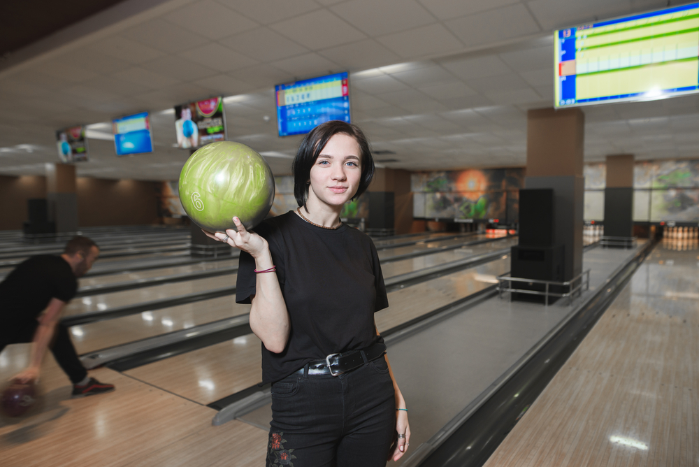 A female bowler takes a photo before her last ball where she hopes to leave one pin standing, just missing a perfect score.