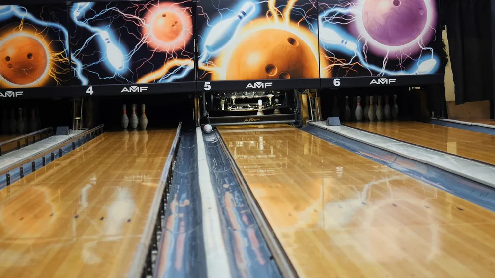 A fun-looking wooden bowling alley lane with ten pins for bowlers preparing to play in local family tournaments.