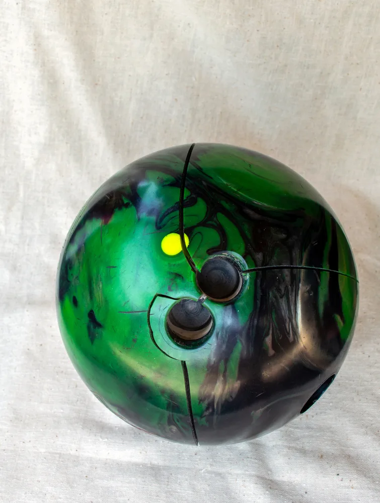 The green cracked bowling ball without finger inserts was replaced with new bowling ball as the owner asked how often should you replace a bowling ball