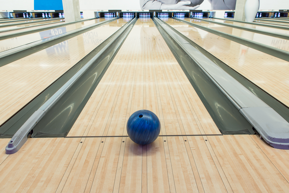 The blue bowling lane sitting on the lane recently hit 2 strikes in a row, then 3 consecutive strikes in the tenth frame.