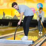 Man and lady, bowling staff, cleaning the lane and gutters before opening