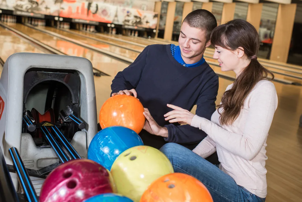 The lady and man in front of the ball return are left handed bowlers.