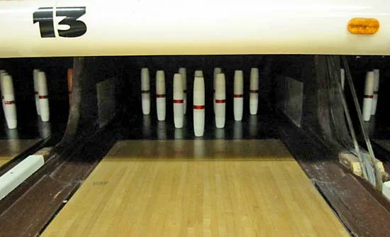 10 candlepin pins are set neatly on the bowling lane.