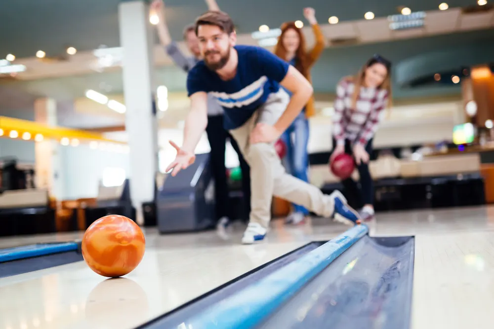 Bowler has the proper bowling equipment bowling ball and bowling shoes while bowling to support local businesses