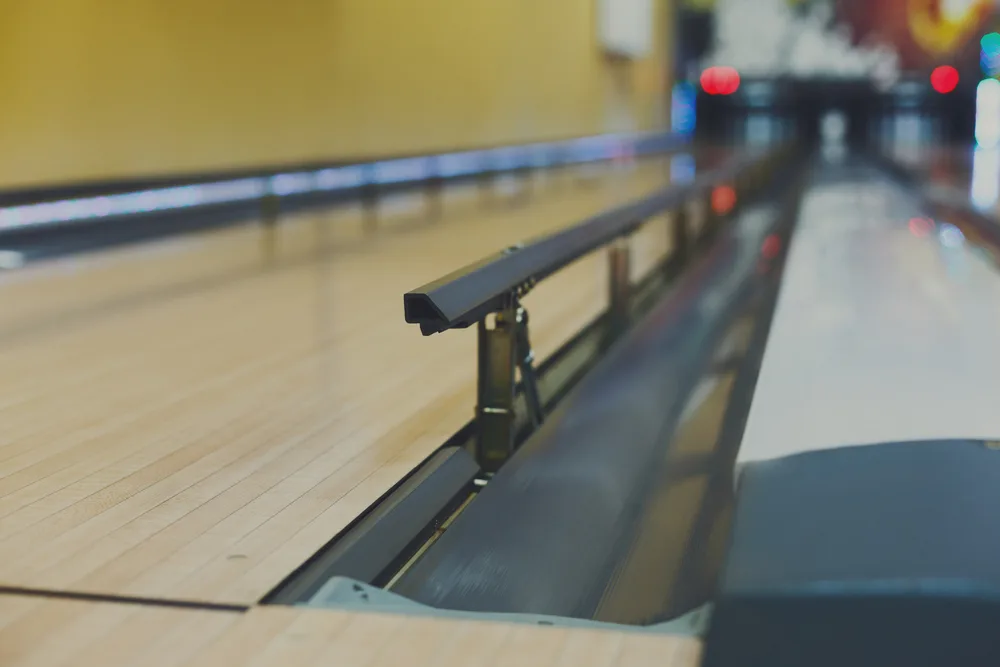 Upclose image of bowling lane, bumpers and foul lane.