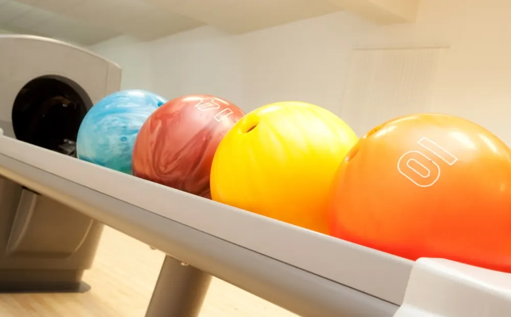 Four bowling balls sit on the ball return and each ball differ in weight