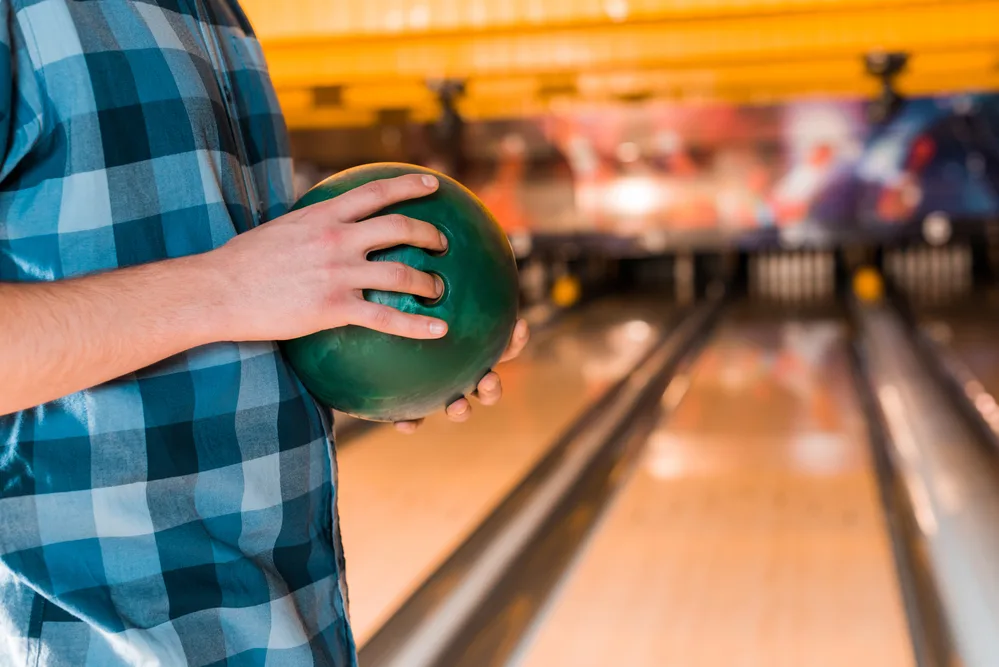 The bowler holding the green bowling ball at the lane with the sphinx pattern is challenged because he has little room for error.