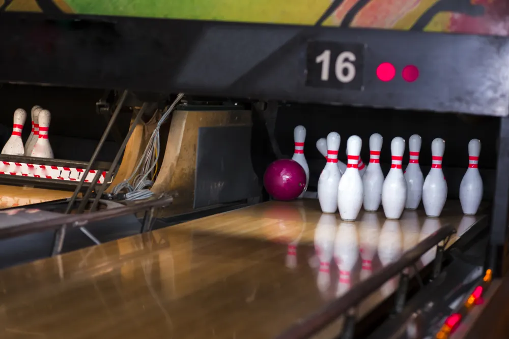 Close up of alley at bowling center with bowling pins in the background and bowling ball was rolled down the middle but hooked right