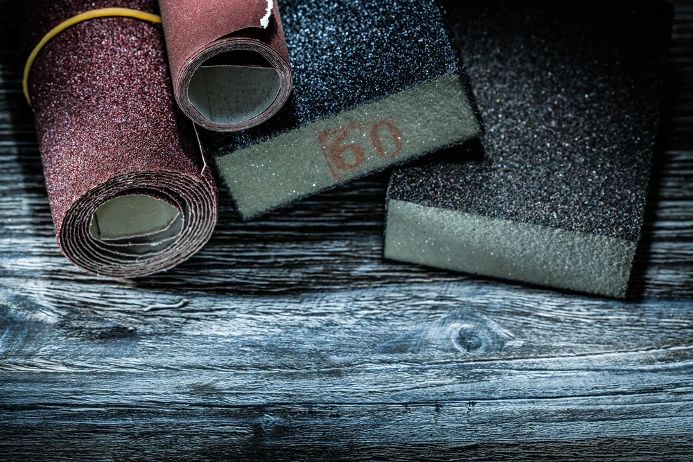 Rolled sanding paper sponges and low grit pad on vintage wooden board