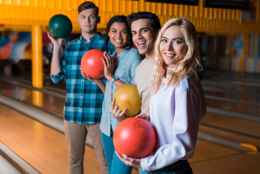 Group of friends standing in front of bowling lane at the alley