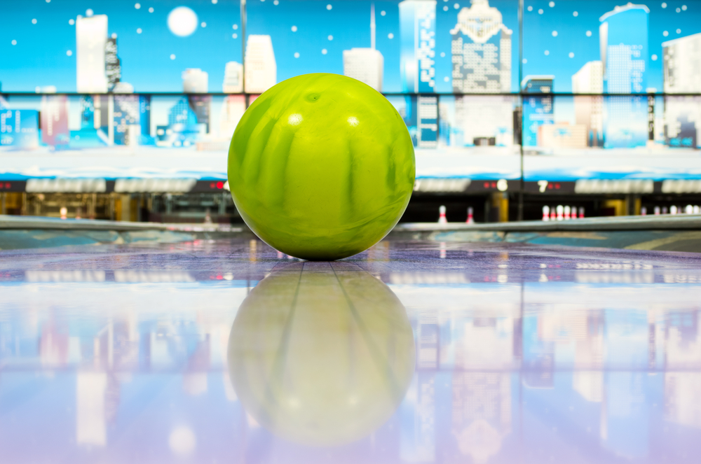 Green sphere ball standing on bowling lane before strike can have up to three ounces static and thumb weight