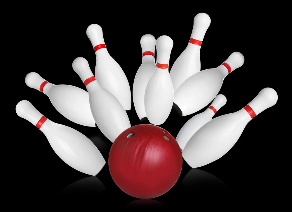 Bowling pins and red plastic bowling balls on black background