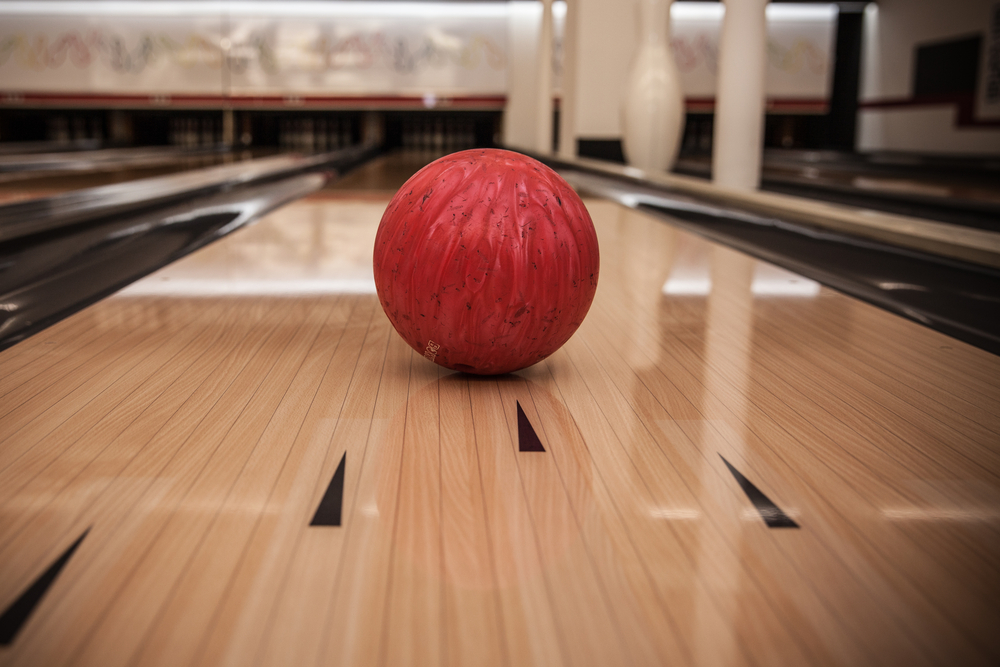 Red bowling ball on a lane with bowling alley in the background the bowler expect it to strike