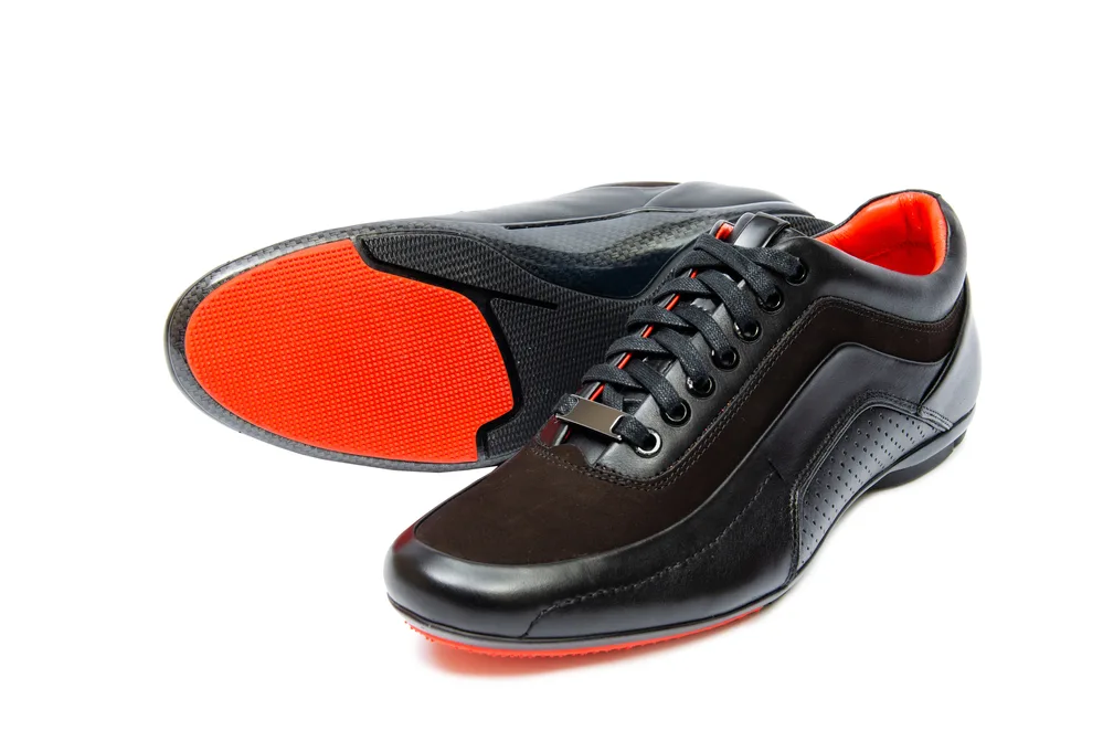 Black bowling shoes with red pads on white background are used at the bowling lane.