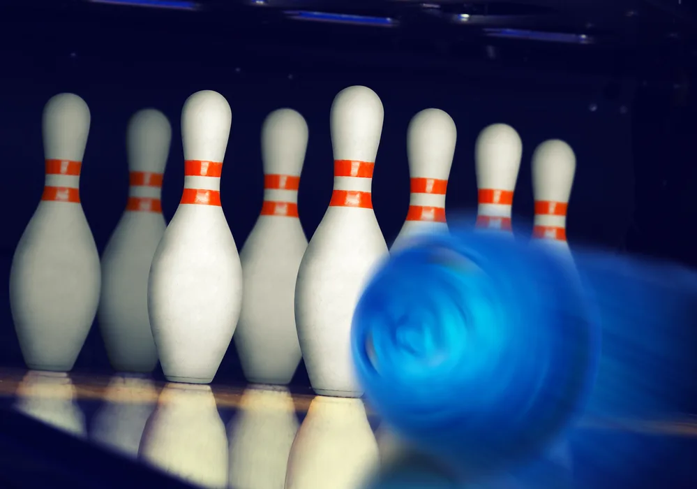 A member of one of the two rival teams bowled a blue bowling ball during the bowling match to decide who was the winner.