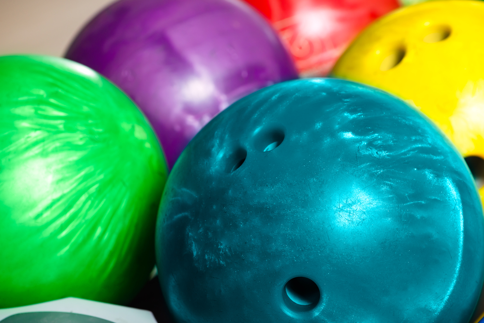 Colorful bowling balls in front of the tenpin alley that were never in a car trunk