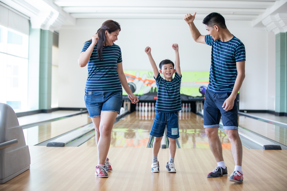 Family having fun at bowling club to expose their son to numerous health benefits