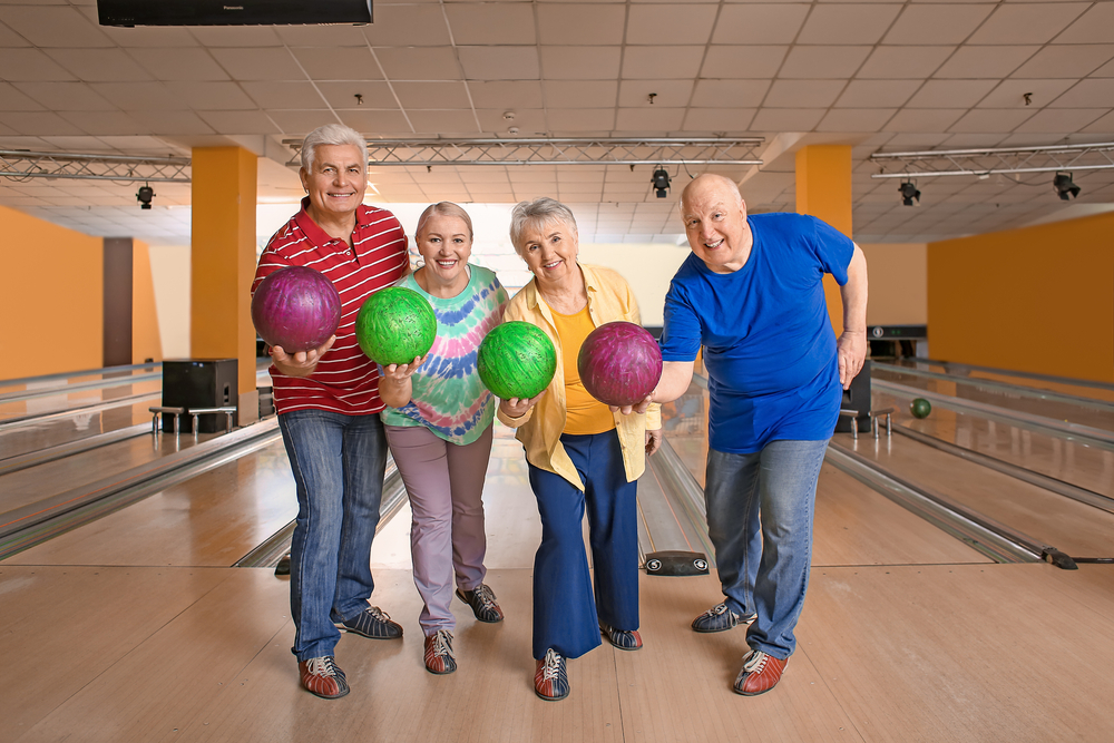 Senior people in bowling club holding bowling balls are apart of the health fitness revolution for their age group
