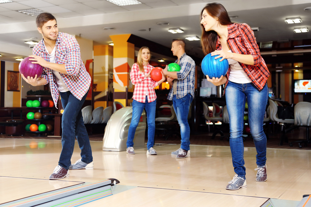 Young friends playing in bowling alley is playing highway to hell that is 40 feet in length.