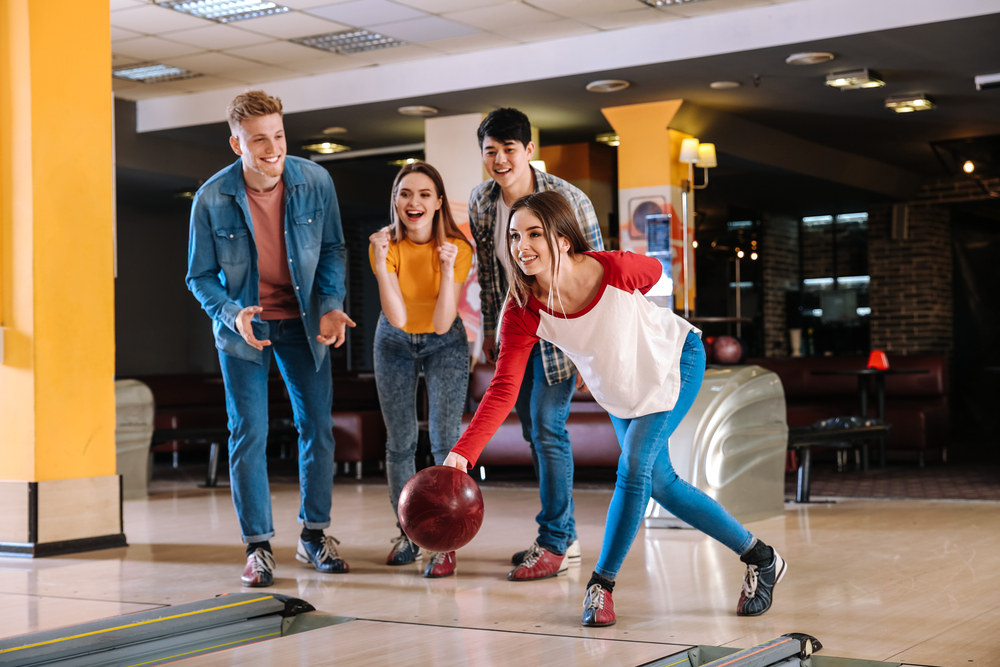 Friends playing bowling in an alley and the lady bowler in the white and red shirt decided to climb the ranking of her friends.
