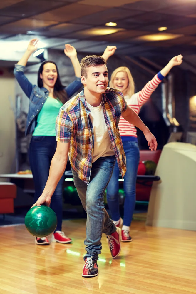 Three bowlers celebrate with high fives after completing their ten frames for the win